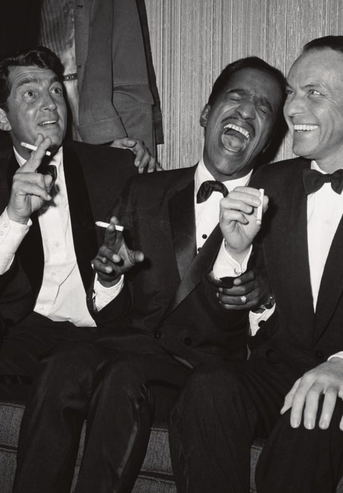 Three men in tuxedos sharing a laugh, black-and-white archival photograph